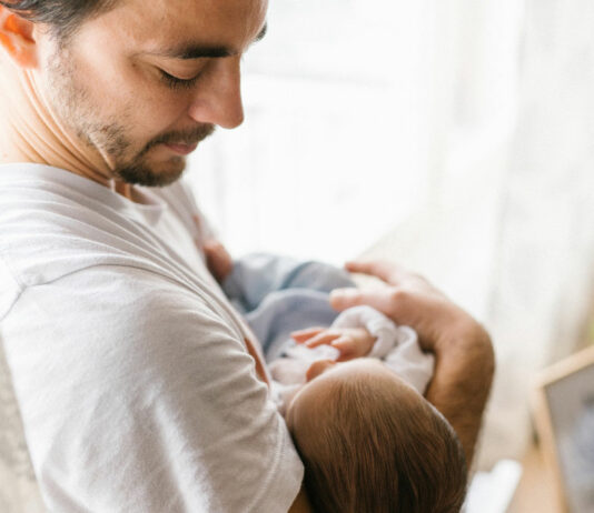 Vater schaut Baby auf dem Arm nachdenklich an