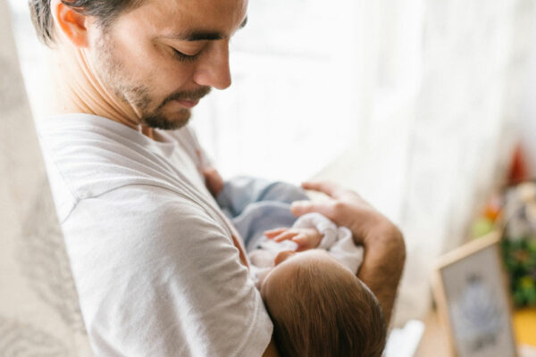 Vater schaut Baby auf dem Arm nachdenklich an