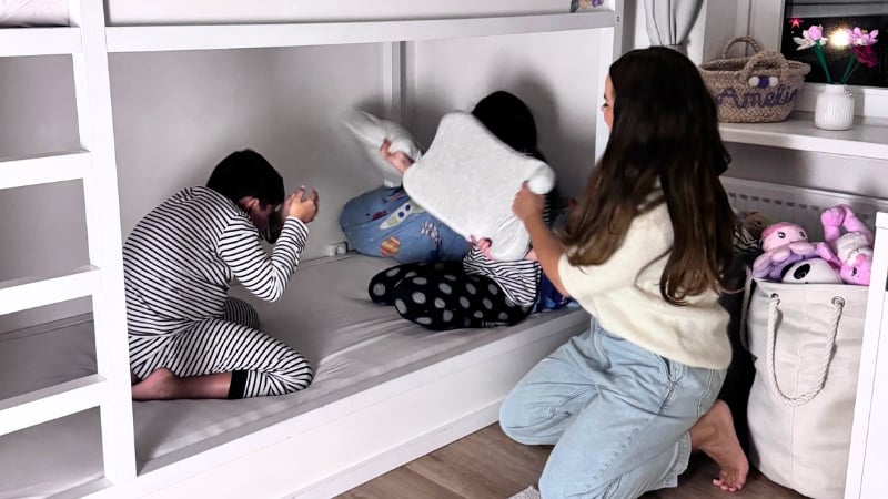 Mama, Soh und Tochter machen eine Kissenschlacht im Bett.